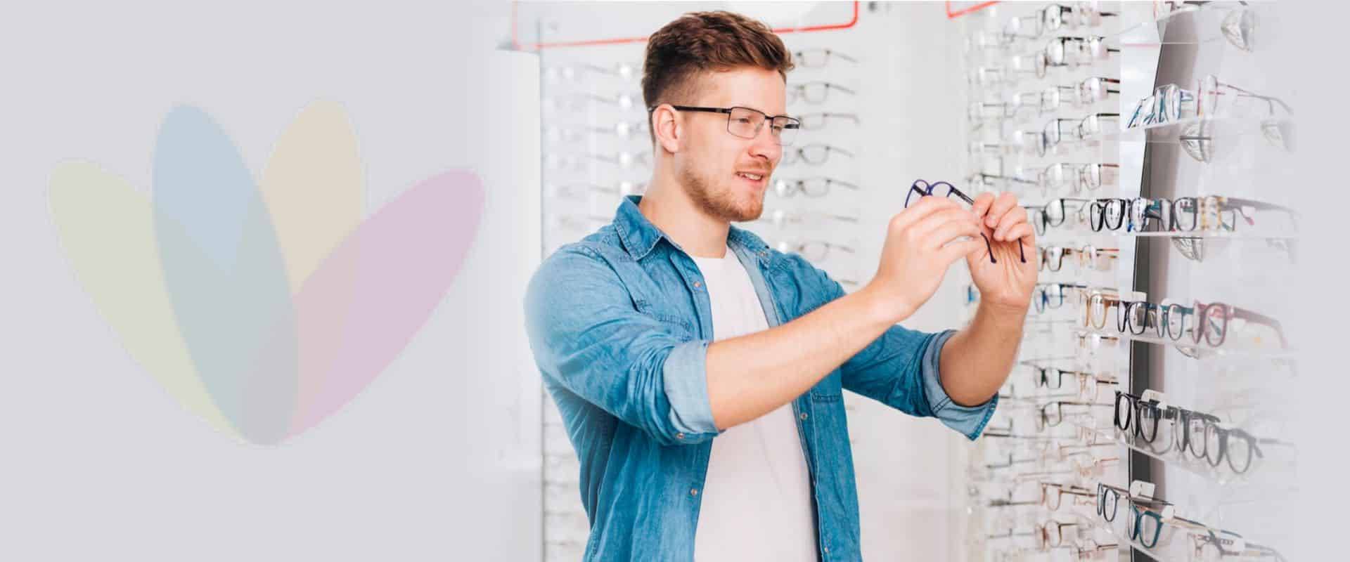 man-examining-a-pair-of-glasses-in-front-of-wall-full-of-glasses man-examining-a-pair-of-glasses-in-front-of-wall-full-of-glasses